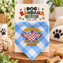 A blue and white gingham dog bandana with a Wonder Woman logo graphic, displayed on its printed packaging card. The card reads 'DOG BANDANA' and includes paw prints.