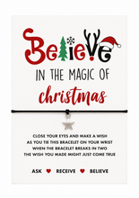 A Christmas-themed bracelet on a black cord with a small silver star charm, displayed on a white card that reads 'Believe in the magic of Christmas' with festive lettering and wish string instructions. Secret Santa gift.