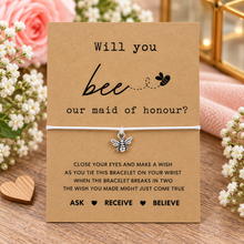 Maid of honour proposal wish string bracelet. A kraft card with the text 'Will you bee our maid of honour?' and a small bee charm tied with a white string. Maid of honour gift 