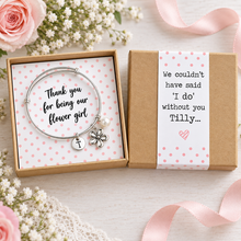 Personalised Thank you for being our flower girl charm bangle. A silver charm bracelet presented in a pink polka dot gift box. The bracelet has a round silver bracelet with a flower charm, a small pearl bead, and a round initial charm. Flower girl gift.
