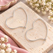 A pair of thin silver heart-shaped hoop earrings created with stainless steel. Heart hoop earrings 
