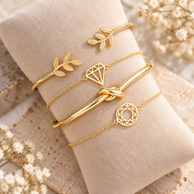 Four gold bangle bracelets set. The bracelets include a gold leaf bangle, gold diamond shaped bracelet. A gold knot bangle 
, and a gold geometric chain bracelet. Gold stacking bracelets 