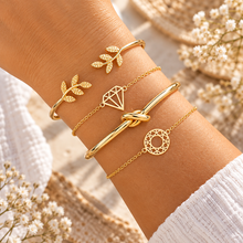 Four gold bangle bracelets set. The bracelets include a gold leaf bangle, gold diamond shaped bracelet. A gold knot bangle 
, and a gold geometric chain bracelet. Gold stacking bracelets 