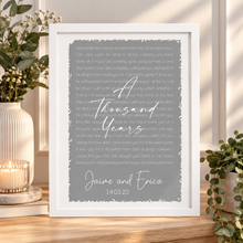 A framed typographic art print with a grey background and white script text reading 'A Thousand Years' lyrics and personalised names/date. First dance song. Wedding anniversary gift 