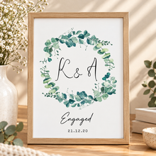 A personalised print with a green eucalyptus wreath and the names 'M & L', plus the text 'engaged' and the date Engagement print with initials 