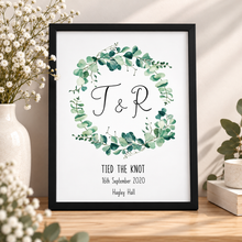 A personalised wedding print featuring a green eucalyptus wreath with the initials 'T & R' and the text 'TIED THE KNOT 16th September 2020 Hagley Hall' customised wedding print